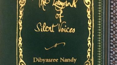 A sample cover of the book: pine green coloured handloom sari with gold embossed nameplate and lettering for the title and author's name. The border of the sari lines the right hand margin of the cover.