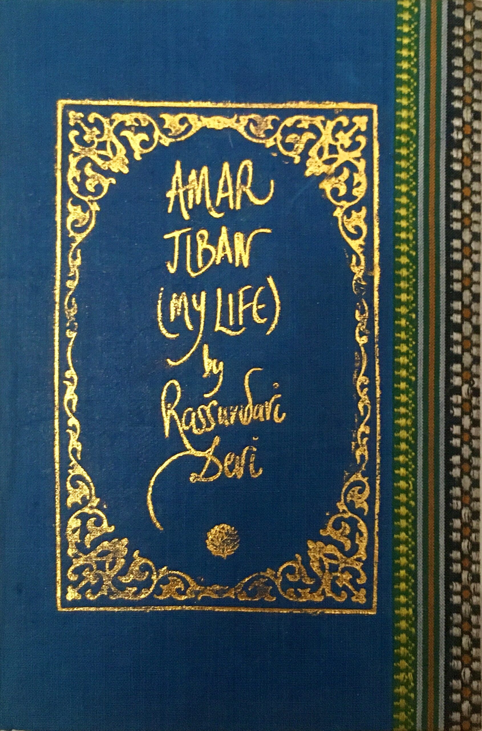 A sample cover of the book: aquamarine coloured handloom sari with gold embossed nameplate and lettering for the title and author's name. The border of the sari lines the right hand margin of the cover.