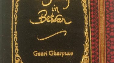 A sample cover of the book: black coloured handloom sari with gold embossed nameplate and lettering for the title and author's name. The border of the sari lines the right hand margin of the cover.
