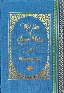 A sample cover of the book: aquamarine coloured handloom sari with gold embossed nameplate and lettering for the title and author's name. The border of the sari lines the right hand margin of the cover.