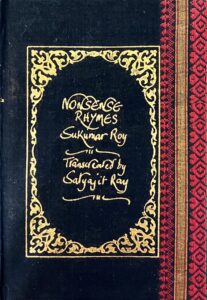 A sample cover of the book: black handloom sari with gold embossed nameplate and lettering for the title and author's name. The border of the sari lines the right hand margin of the cover.
