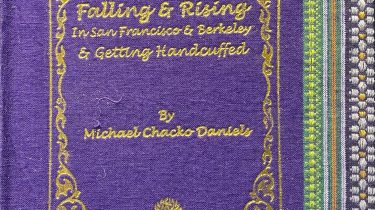 A sample cover of the book: purple handloom sari with gold embossed nameplate and lettering for the title and author's name. The border of the sari lines the right hand margin of the cover.